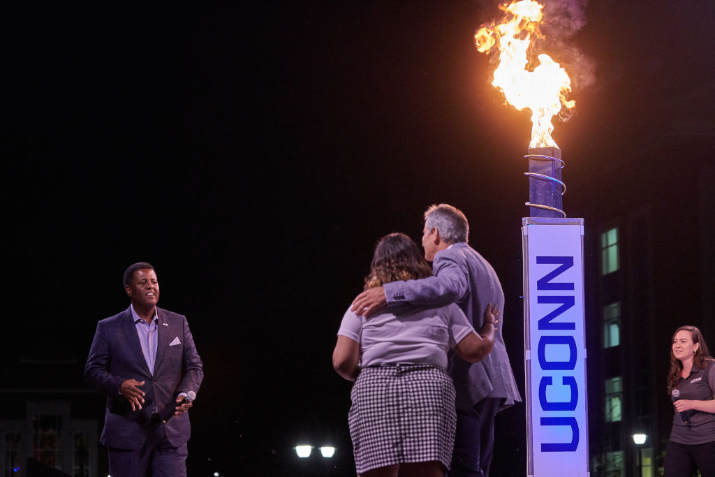 President Tom Katsouleas hugs USG President Priyanka Thakkar '20 (BUS) after the torch was lit at the Convocation ceremony on the Student Union Mall on Aug. 23, 2019. At left is Vern Granger, director of undergraduate admissions. At Right is Kailee Himes '15 (CLAS), a graduate student. (Peter Morenus/UConn Photo)