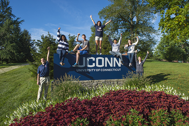 Students cheer while standing with the University sign near the corner of North Eagleville and RT 195 on Sept. 6, 2013. (Peter Morenus/UConn Photo)